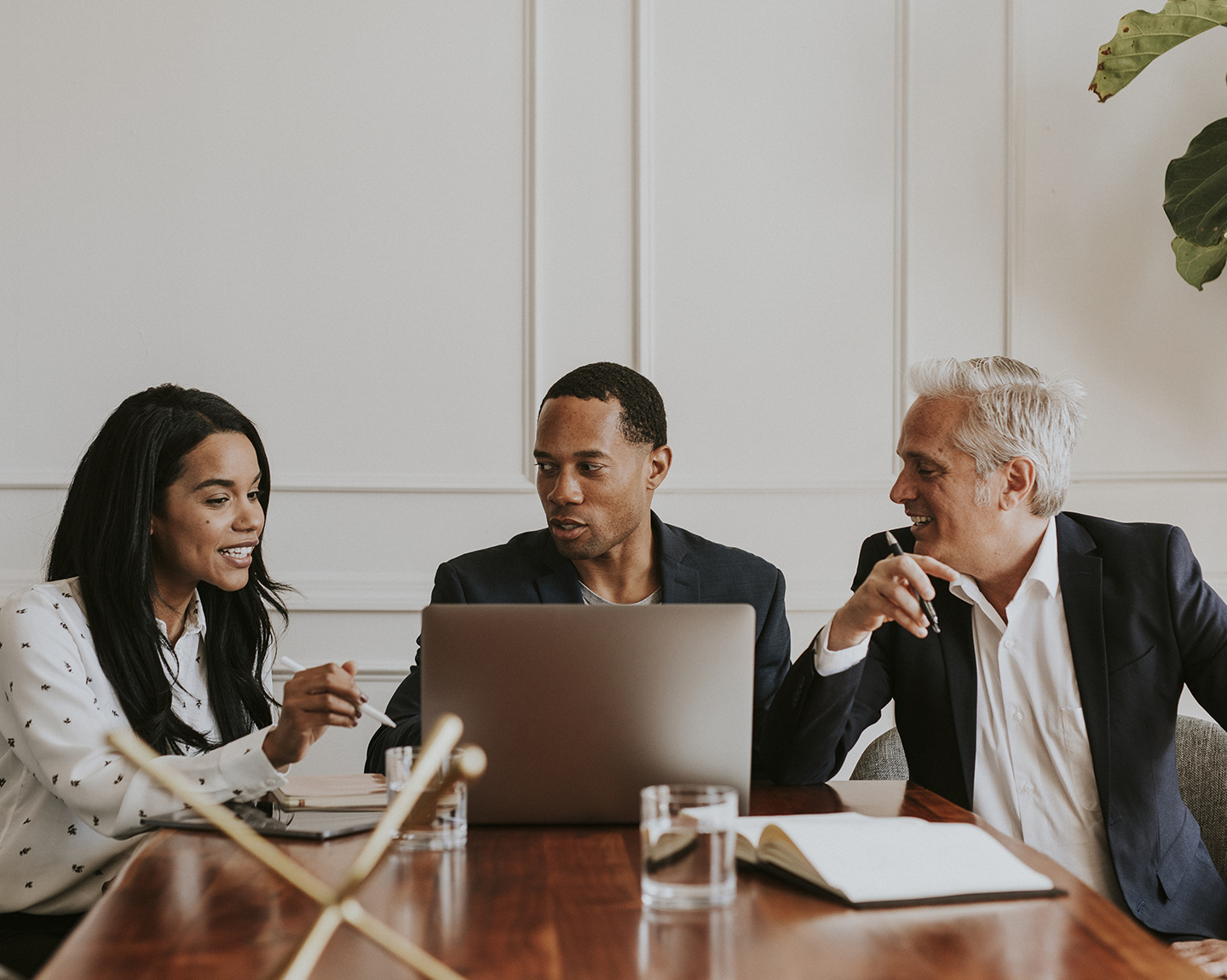 Businesspeople converse around a computer