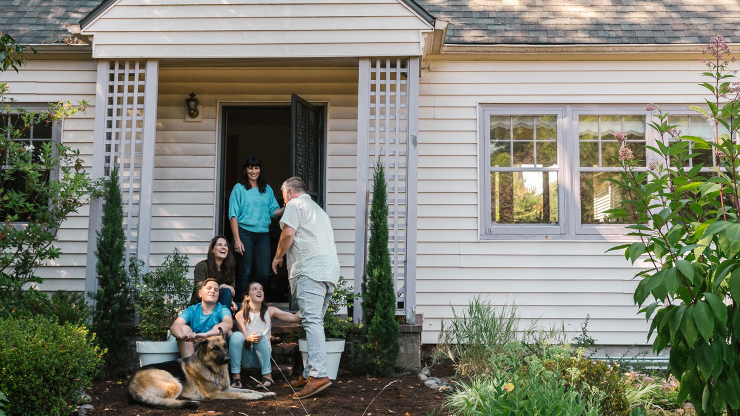 Smiling family outside of house